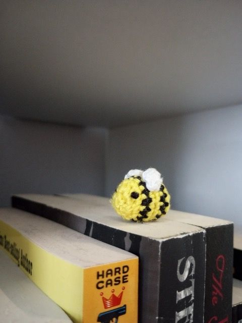 Yellow and black crochet bee on top of a book.