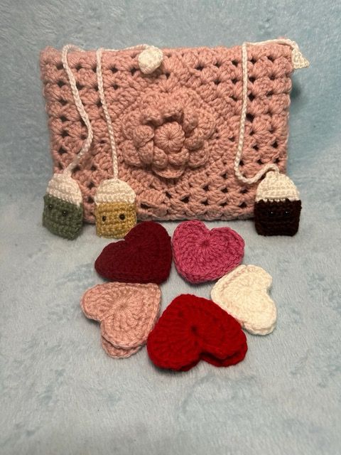 A pink book sleeve, three tea bag bookmarks, and five heart bookmarks are in front of a white background.