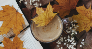 a book with a mug and autumn leaves