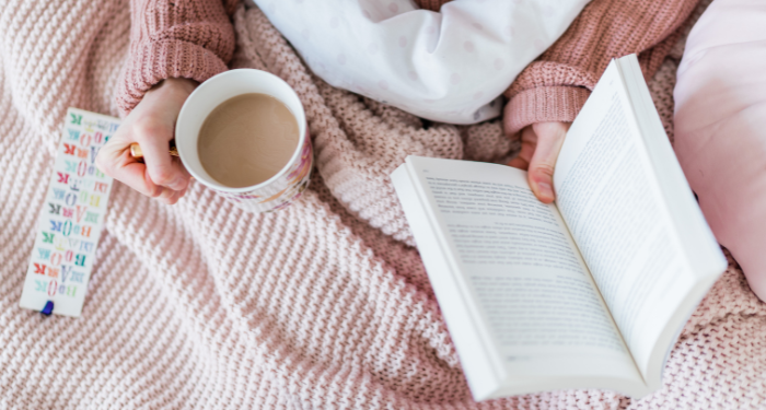 someone reading in bed with a cup of tea