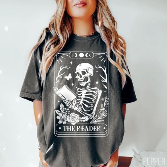 image of a black tshirt with a skeleton reading and a tarot card titled The Reader 