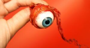 a hand holding an eyeball against a bright red backgroud