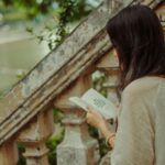 a fair-skinned woman reading on antique steps