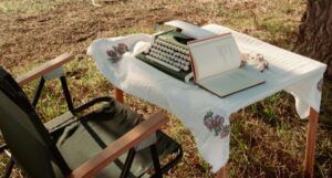 cover of a typewriter and a book on a table outside