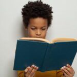 a young Black boy reading a hardcover book