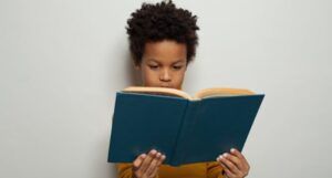 a young Black boy reading a hardcover book