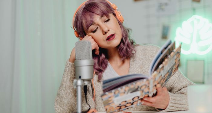 fair-skinned white woman with podcast equipment reading a book