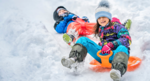 two kids sledding in the snow