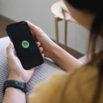 a person holding up a phone with the Spotify logo