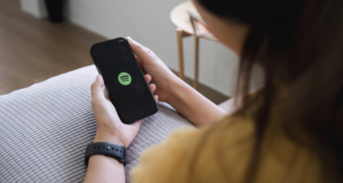 a person holding up a phone with the Spotify logo