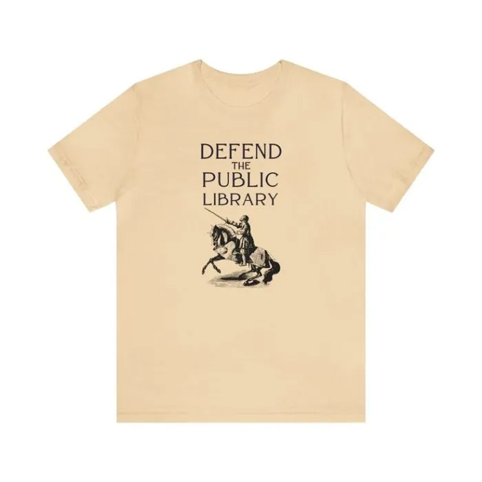 ivory short sleeve tshirt with a vintage image of a knight on a horse and text reading Defend the Public Library