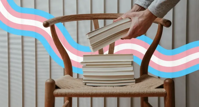 a chair with books on it and a trans rainbow flag design behind it